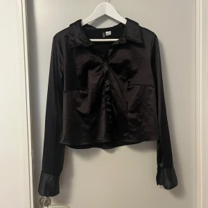Svart H&M divided croppad tröja stl XL - Glansig tyg. stl XL som motsvarar ca 44 (på mig som 42/44) blus eller croppad tröja..lite osäker men det är väll smaksak. Sparsamt använd då jag inte trivdes i croppad :) 