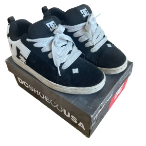 Svarta DC 'Court Graffik' sneakers med vit logga - Klassiska DC Court Graffik sneakers i svart mocka med stor vit DC-logga på sidan och vita snören. Skick 6/10, ganska väl använda men inte riktigt några synliga brister. Endast fransiga i sulan där fram, utöver det inget markant. Bara att höra av sig vid eventuella frågor😁