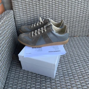 Maison Margiela Gats sneakers - Maison Margiela sneakers i olivgrön med ovandel i mocka och skinn, klassisk gummisula och vita snören. Snygg retrostil med rund tå och diskret branding på plösen. Perfekta för dig som gillar minimalistisk och stilren design. Har endast testats innan, kvitto följer med på köpet såklart.
