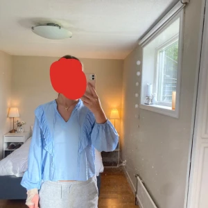 Ljusblå Blus - En ljusblå långärmad blus med volanger samt snörning. Inga fläckar eller liknande på den och väldigt bra skick. Storlek S från Kappahl.