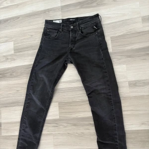 Replay Grover svarta jeans, stl 29 - Säljer ett par svarta Replay Grover jeans i klassisk femficksmodell. Jeansen har en snygg , raka ben och normal passform. Märkespatch bak i midjan och diskreta detaljer på bakfickan. Perfekta för dig som gillar stilrena svarta jeans. Ny pris 1500