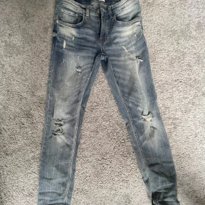 Blå slitna skinny jeans från Redefined REBEL - Snygga blå skinny jeans från REBEL med slitna detaljer och hål på benen. Jeansen har klassisk femficksdesign, normal midja och är tillverkade i stretchig denim för en bekväm passform. Perfekta för en avslappnad och trendig look.