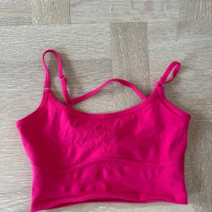 Rosa linnetopp med smala axelband - Snygg rosa linnetopp med smala, justerbara axelband. Toppen är croppad och har en enkel, stilren design som passar perfekt till jeans eller kjol. Gjord i mjukt material som känns skönt mot huden.