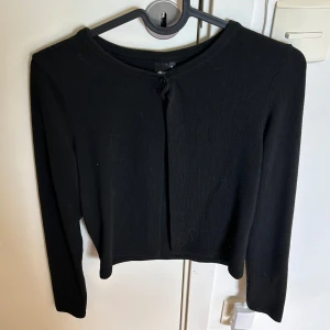 Svart kofta  - Säljer denna svarta kofta från Gina Tricot i storlek S. Modellen är lite croppad med lång ärm och rund halsringning. Koftan har en knapp upp till. 