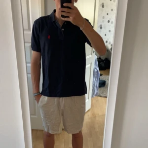Mörkblå pikétröja från  Polo Ralph Lauren - Tjena säljer nu min snygg mörkblå pikétröja från Polo Ralph Lauren i slim fit. Klassisk design med krage, knappar och röd broderad logga på bröstet. Tillverkad i mjuk bomull och har korta ärmar. Perfekt för varma dagar nu på sommaren skick 10/10 Inga tecken på användning. Priset är inte hugget i sten!