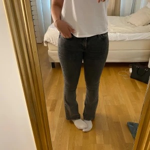 Mörkgrå bootcut jeans - Snygga mörkgrå jeans med bootcut-modell och klassisk femficksdesign. Jeansen har en låg/medel midja och är tillverkade i ett stretchigt denimtyg som sitter bekvämt. Perfekta för dig som gillar en tidlös och trendig look.