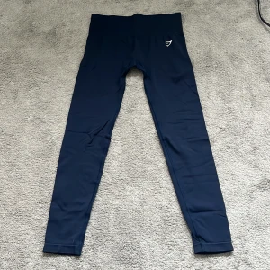 Mörkblå leggings från Gymshark - Snygga mörkblå leggings från Gymshark med skön och tight passform. Diskret logga på höften och stilren design. Använda ett fåtal gånger.