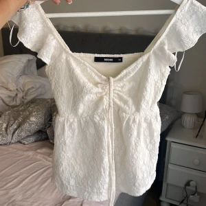 Vit blus med knyt  - Supersöt vit blus från BikBok med knyt framtill och lätt volang vid axlarna