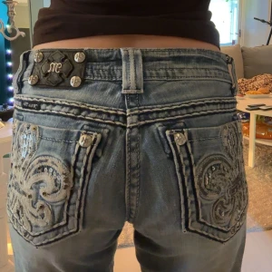 Miss Me lågmidjade jeans - Säljer ett par blåa bootcut jeans från Miss Me med snygga broderade och paljettprydda bakfickor. Jeansen blir mer utsvänga nedanför och har låg midja. Midjan är rätt stretchig också. Användt en gång och mycket bra skick. Midjemåttet är 35 rakt över,(sista bilden. Innerbenslängd är 77 cm. Skriv privat om du har frågor, pris kan diskuteras!💞