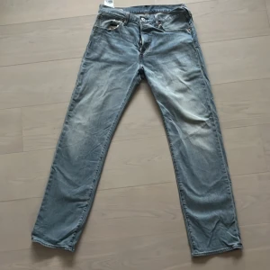 Levis 501 ljusblå jeansbyxor - Klassiska Levis 501 jeans i ljusblå tvätt med raka ben och femficksmodell. Byxorna har knappgylf och passar en avslappnad look. Perfekta för dig som gillar tidlös denimstil.