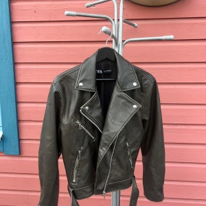 Grön skinnjacka från Zara - Snygg grön skinnjacka från Zara. Använd fåtal gånger. Detta är en ”längre” modell än den korta versionen.  Storlek S.