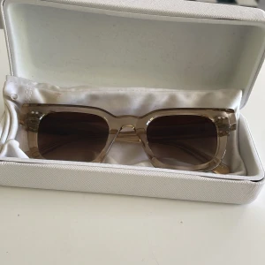 Beige solglasögon från CHIMI - Snygga solglasögon från CHIMI i beige transparent plast med rektangulära bågar och bruna tonade glas. Perfekt accessoar för att lyfta din stil under soliga dagar.