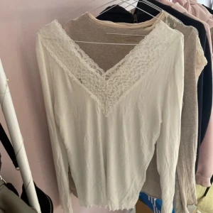 Vit långärmad topp med spetsdetalj - Säljer en vit långärmad topp med v-ringning och bred spetsdetalj framtill, skriv vid frågor❤️