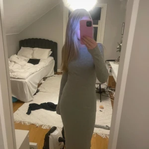 Ljusgrå tight långärmad klänning - Säljer en ljusgrå, tight och långärmad klänning med rund halsringning. Klänningen är figurnära och har en enkel, stilren design som passar perfekt till många tillfällen.