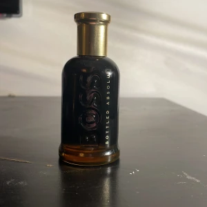 BOSS Bottled Absolu herrparfym - Elegant herrparfym från Hugo Boss, Bottled Absolu. Flaskan är svart med guldigt lock och har en stilren, maskulin design. Perfekt för dig som gillar exklusiva dofter och snygga flaskor i badrumshyllan.