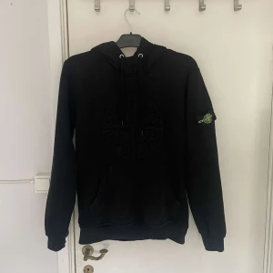 Svart hoodie från Stone Island - Säljer en svart hoodie från Stone Island med klassisk logga på armen och på bröstet | Perfekt för en avslappnad och stilren look | Tröjan är väl omhändertagen och är i bra skick | 
