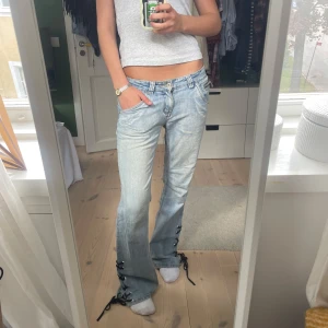 Ljusblå jeans med snörning och dragkedjor - SKIIIT snygga jeans med snörning nertill! Märket är BHL och storlek är 36-38!.