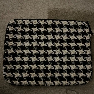 Svartvit rutig datorväska - Säljer en datorväska med klassiskt svartvitt rutigt mönster. Väskan har dragkedja upptill och är perfekt för att skydda din laptop. Stilren och passar till många olika tillfällen.