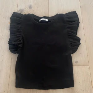Svart topp med volangärmar från Zara - Säljer en svart topp från Zara med stora volangärmar eftersom den inte kommer till användning längre. 