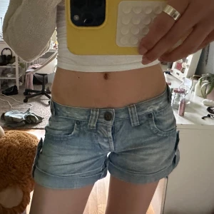 Ljusblå jeansshorts från Guess Jeans - Super lågmidjade, ljusblåa jeansshorts från Guess. Jättecoola spännen och fickor! Skriv för mått eller fler bilder🤗