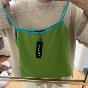 Grönt linne med blåa band - Säljer ett så fint grönt linne med blåa band. Såå najs i sommar🙌🙌💝💝 aldrig använd-prislappen är kvar.                                                 (OBS: tryck INTE på köp nu utan att jag har bekräftat att du kan köpa plagget)