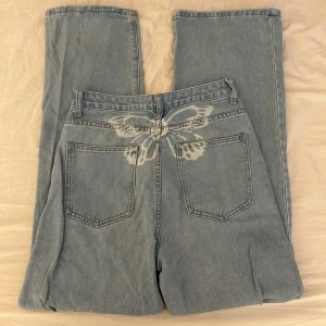 Ljusblå jeans med fjärilsdetalj - Ljusblå wida jeans i strl S med söt fjäril på baksidan. 