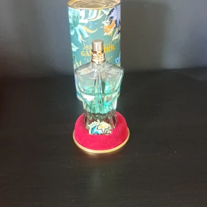 Jean Paul Gaultier Le Beau Eau de Parfum - Säljer en Jean Paul Gaultier Le Beau Eau de Parfum i en unik turkosgrön flaska formad som en manlig torso. Flaskan har gulddetaljer och kommer med originalförpackning med drakmotiv och röd sammetsbas. Pris kan diskuteras!