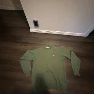 Grön ulltröja från Burberry - Säljer en klassisk grön tröja från Burberry i mjuk ull. Tröjan har rund halsringning och långa ärmar. Liten broderad Burberry logga på bröstet. Perfekt för dig som gillar stilrena och tidlösa plagg. Tröjan har inga yttre defekter, men har dessvärre tvättlapparna blivit urtvättade och att tagen har lossnat med ett stygn annars jätte fin, pris kan diskuteras vid smidig affär🙌