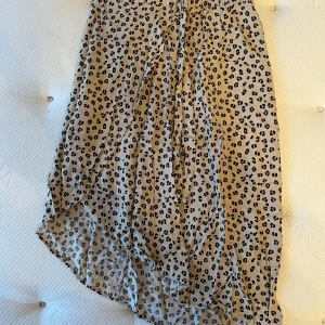 Beige leopardmönstrad kjol från KappAhl - Säljer en beige kjol från KappAhl med svart leopardmönster. Kjolen har resår i midjan och är lätt och luftig med en något asymmetrisk nederkant. Perfekt för dig som gillar djurmönster och vill ha en skön kjol till sommaren.