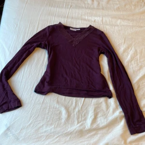 Vinröd långärmad topp med spets från Gina Tricot - Säljer en vinröd långärmad topp från Gina Tricot.💗 Toppen har v-ringning med fina spetsdetaljer längs halsen och är tillverkad i mjukt bomullsmaterial. Perfekt för dig som gillar en enkel men ändå söt stil. Har en pytteliten vit fläck som knappt syns💘