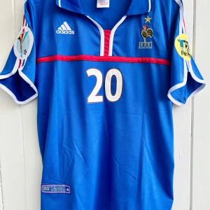 David Trezeguet - Frankrike EM 2000 - Säljer en klassisk fotbollströja, David Trezeguets matchtröja från EM 2000 när avgjorde så att hans Frankrike vann över Italien och blev Europamästare. Tröjan är en remake i nyskick. Aldrig använd.  Large, normal i storleken.  Skickas inom 24 h. #fotboll 