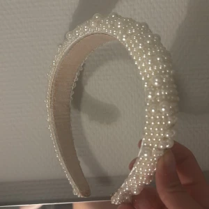 Vitt diadem med pärlor - Snyggt diadem i vitt dekorerat med massor av små och stora pärlor. Perfekt accessoar för att lyfta din look med en elegant touch. Bred modell som sitter bekvämt på huvudet.