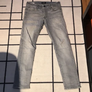 Grå slim jeans Jack & Jones Glenn 30/30 - Säljer ett par ljusgrå slim fit jeans från Jack & Jones, modell Glenn. Jeansen har klassisk femficksdesign, normal midja och raka ben med smal passform. Tillverkade i mjuk bomullsdenim med snygg tvättad look.