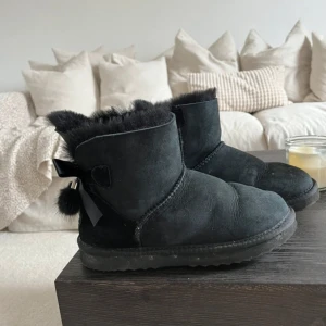 Svarta pälsfodrade boots med rosett - Svarta boots från med fluffigt pälsfoder, rosett och metall-detaljer bak. I storlek 36