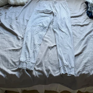 Randiga mjukisbyxor i bomull - Superbekväma mjukisbyxor med gråvita ränder och muddar vid bensluten. Perfekta för chill hemma eller när du vill vara extra comfy. Resår i midjan och mjukt bomullsmaterial gör dem till ett måste i garderoben.