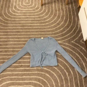 Ljusblå omlottkofta från Outfitters - Supermjuk och fluffig ljusblå omlottkofta från Outfitters. Croppad modell med långa ärmar och knyt framtill. 