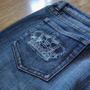 Victoria Beckham x Rock & Republic bootcut jeans - Snygga ljusblå bootcut jeans med broderad krona och VB-logga på bakfickan. Klassisk femficksmodell med coola detaljer och lätt slitning. Perfekta för dig som vill sticka ut med en unik och trendig denimstil.