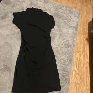 Svart kortklänning från Missiny - En stilren svart kortklänning från Missiny med figurnära passform och korta ärmar. Klänningen har en enkel design, är perfekt för dig som gillar en klassisk look.