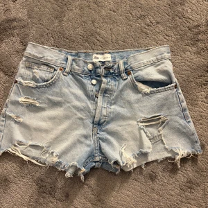 Ljusa jeansshorts från Zara - Snygga ljusblå jeansshorts från Zara med slitna detaljer och fransig kant. Klassisk femficksmodell med knappar i gylfen. Perfekta för en chill sommarlook.