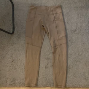 Tränings byxor - Ett par tränings byxor som är  beige med fickor