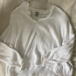 Vit stickad tröja med spets från Stajl - Superfin vit stickad tröja från Stajl med v-ringning och spetsdetaljer runt halsen. Tröjan har långa ärmar och ribbade muddar. Perfekt för dig som gillar en romantisk och chill vibe. Passar till både jeans och kjol.