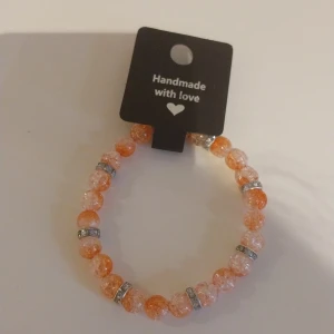 Handgjort orange pärlarmband - Superfint handgjort armband med glittrande orange och ljusa pärlor, dekorerat med silvriga detaljer mellan pärlorna. Perfekt accessoar för att ge lite färg till din outfit. Elastiskt band gör det enkelt att ta på och av.
