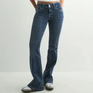 Blå bootcut jeans med broderade fickor - Snygga blå bootcut jeans med låg midja och coola broderade bakfickor. Jeansen har klassisk femficksdesign, dubbla knappar i midjan och är gjorda i stretchig bomullsdenim. Perfekta för dig som gillar en retro vibe och vill ha en bekväm passform. Lite slitningar på ena fickan av jeansen   där av priset❤️