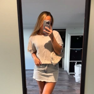 Beige randig blus från Vila - Säljer en beige blus från Vila med tunna vertikala ränder och volangiga, korta ärmar. Toppen har rund halsringning och en lätt loose passform, perfekt för en chill och stilren look. Superfin till jeans eller kjol!