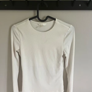 Vit ribbad långärmad topp - Vit långärmad topp från H&M i ribbat material. Tight passform med rund halsringning. Endast använd 1-2 gånger. 