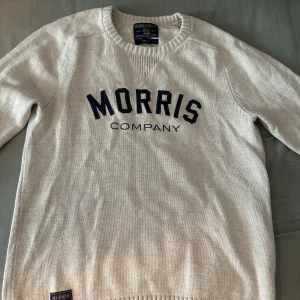 Vit tröja från Morris - Säljer en stilren vit tröja från Morris med mörkblå text på bröstet. Tröjan har en rund halsringning och långa ärmar. Perfekt för en avslappnad look.