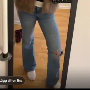 Blå jeans med hål på ena knät. De är från Gina och har gjort hålet själv. De har gått sönder i skrevet och har sy ihop lite men man kan sy mer så de blir hela, därav billiga priset. 