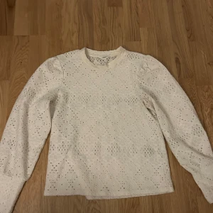 Vit spetsblus från Object - Säljer en elegant vit spetsblus från Object. Blusen har ett vackert spetsmönster och långa ärmar. Perfekt för en stilren look. Passar bra till både jeans och kjol. Tyvärr en fläck runt halsen
