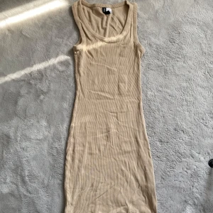 Beige ribbad klänning från Hm - Säljer en stilren beige ribbad klänning från HM. Klänningen är ärmlös och har en kroppsnära passform som framhäver figuren. Perfekt för en avslappnad och trendig look.