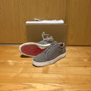 Christian Louboutin Grå  - Säljer nu dessa feta grå sneakers i mocka från Christian Louboutin med den kända röda sulan. Perfekta för dom som vill ha fräscha skor nu till sommaren, tveka inte på att höra av er vid frågor och såklart är priset ej hugget i sten😊